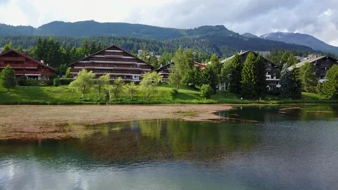 Fly over lake with beautiful chalets in rural switzerland in the mountains Stock Footage 128733115