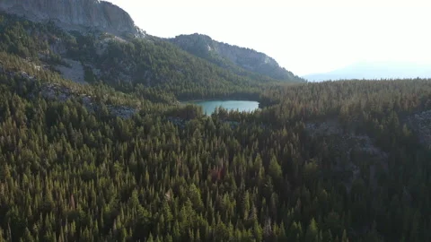 Fly over lush forest towards a clear blue lake on the mountain Stock Footage 142963632