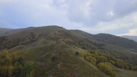 Fly over mountain peaks covered with bushes and forest in autumn. Stock Footage 145803559