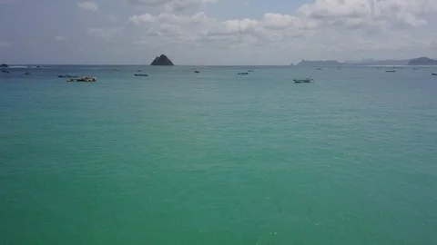 Fly over open turquoise idyllic sea toward rock Stock Footage 129047076