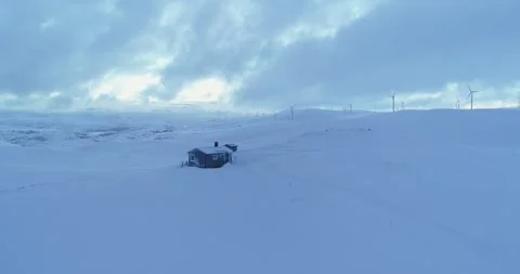 Fly over: Remote Winter cabin with wind power plant background Stock Footage 152785425