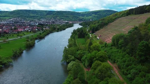 Fly over the river along the countryside road next to the vineyard and town Stock Footage 154375069