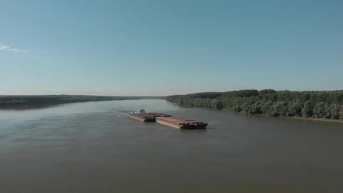 Fly over a river bordered by extensive forests on which sail a barge loaded Stock Footage 129936242