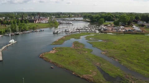 Fly over a river facing an old boat yard with a large brick building - aerial Video stock 161032385