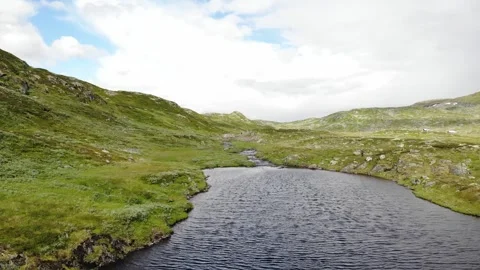 Fly over a river or lake and reveal a girl walking in background in Norway Stock Footage 248364859