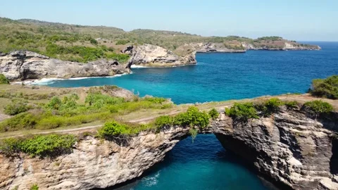 Fly over rock arch over ocean in Broken Beach Stock Footage 159640099