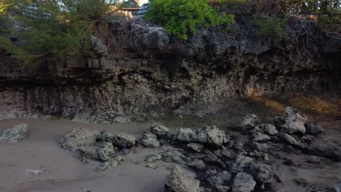 Fly over small rock cliff in low tide in sunset Stock Footage 155550578