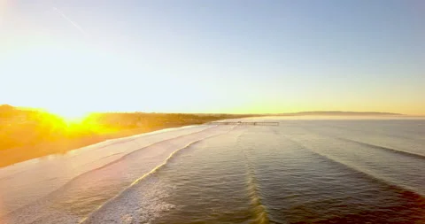 Fly over waves towards pier at sunrise. 4k Aerial Stock Footage 145272006