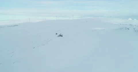 Fly by remote snowy winter cabin in the arctic with wind power plant Stock Footage 152785478