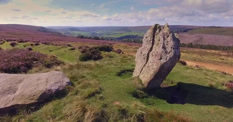 Fly up from standing stone to flowering heather - Bransdale North Yorks Moors Stock Footage 72654073