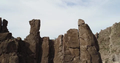 Fly through gap in rocky outcrop to reveal bridge and town drone aerial 4K Stock Footage 111312308