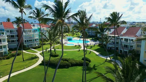 Fly-through palm trees towards luxury tropical residential estate, swimming pool Video stock 309568109
