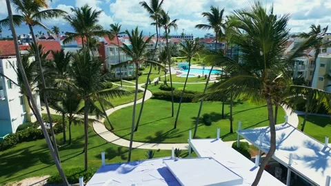 Fly-through palm trees towards luxury tropical residential estate, swimming pool Stock Footage 309941217