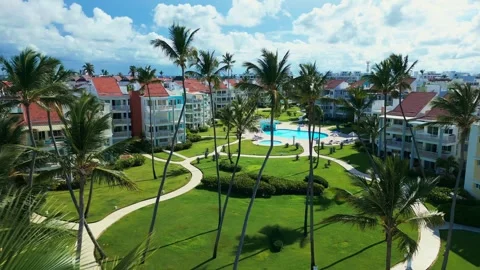 Fly-through palm trees towards luxury tropical residential estate, swimming pool Stock Footage 311339276