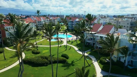 Fly-through palm trees towards luxury tropical residential estate, swimming pool Stock Footage 311339444