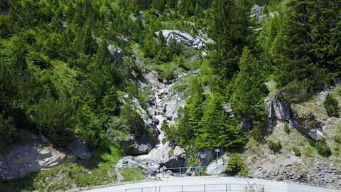 Fly-through river around a corner in mountain to waterfall with green trees Stock Footage 128699383