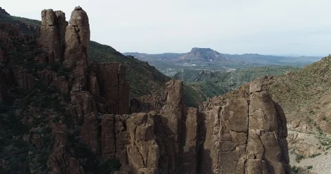 Fly through rocks reveals bridge, town and mountain drone aerial 4K Stock Footage 111312163