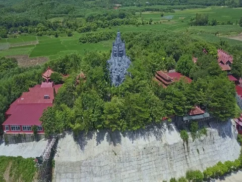 Flycam Approaches Large Statue among Trees on Temple Hill Stock Footage