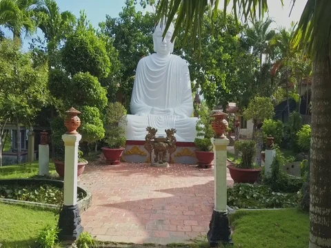 Flycam Approaches White Buddha Statue among in Tropical Park Stock Footage