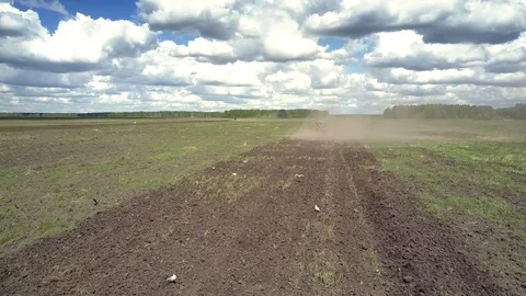 Flycam follows tractor in dust cloud and birds on furrow Stock Footage 104254351