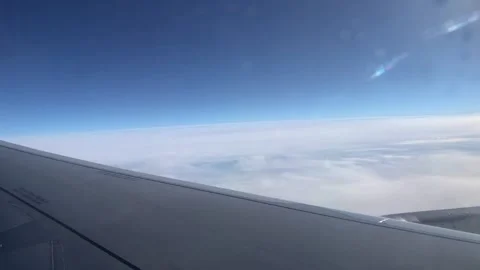 Flying above the clouds on an airplane. View through the porthole on the wing Stock Footage 201890552