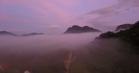 Flying above clouds between mountains with a view on a city down below Stock Footage 108469407