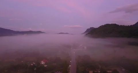 Flying above clouds between mountains with a view on a city down below, Khao Yai Stock Footage 108469457