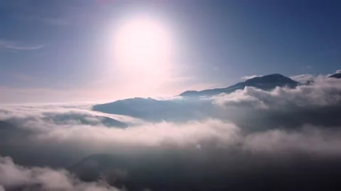 Flying above the clouds with blue sky and sun in front Stock Footage 234641161
