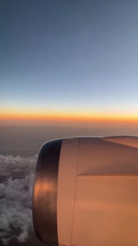 Flying above the clouds during sunset from aircraft window film, panning left Stock-Footage 334691920