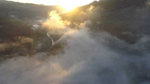 Flying above clouds by mountains during sunrise. Sun shining everywhere, sun Video stock 129424986