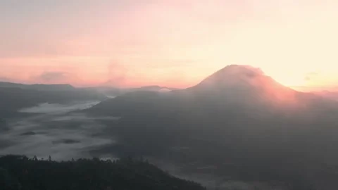 Flying above the clouds next to the volcano at sunrise Stock Footage 142986477