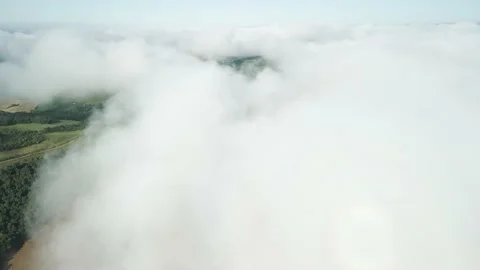 Flying above the clouds over beautiful green fields and a river. Low clouds. Stock Footage 233217997