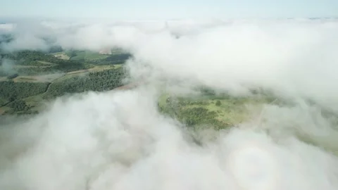 Flying above the clouds over beautiful green fields and a river. Low clouds. Video stock 233218020