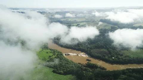 Flying above the clouds over beautiful green fields, pasture and a river. Video stock 233218058