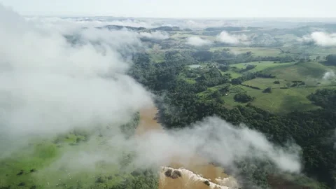 Flying above the clouds over beautiful green fields, pasture and a river. Stock Footage 233218276