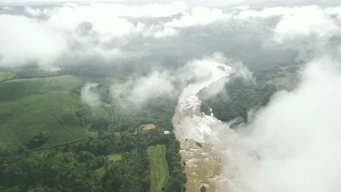 Flying above the clouds over green fields, forest and river. Low clouds. Fog. Video stock 233218488