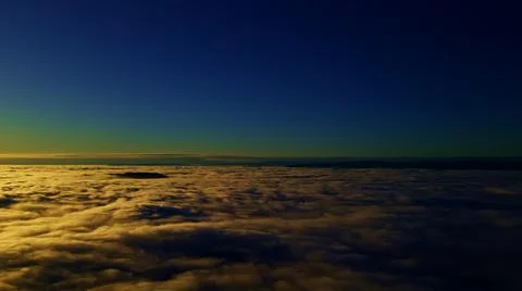 Flying above the clouds into the sunset with deep blue and black skies above. Stock Photos