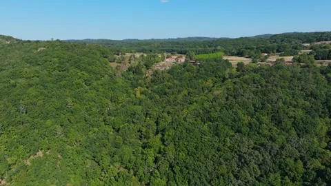 Flying Above Forested Mountain Towards Farmhouse And Fields Stockbeeldmateriaal 285759111