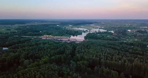 Flying above freight train on the railway bridge, flood-meadow in the twilight Stock Footage 106100272