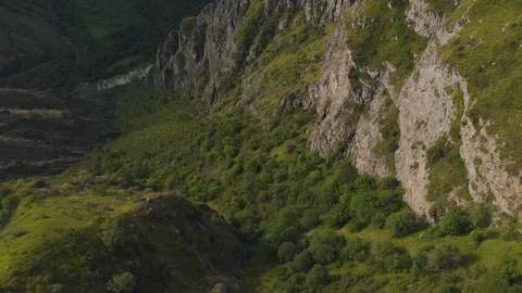 Flying above green gorge between rocky slopes of armenian mountains. Sunset time Stock Footage 94426989