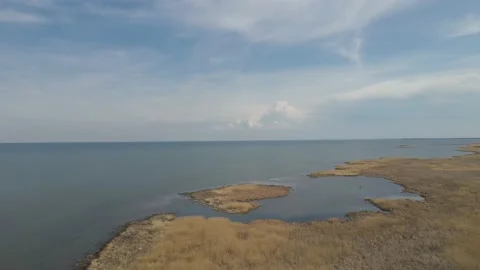 Flying above a large lake with a dry looking marsh. The sky is blue  Stock Footage 155169361