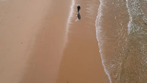 Flying Above Man Walking on Ocean Beach Stock Footage 85488623