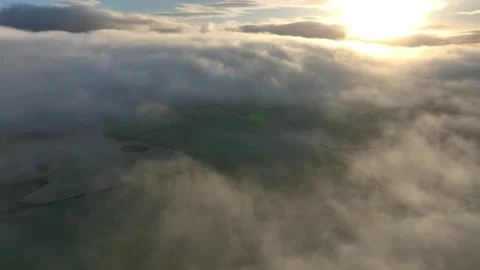 Flying above patchwork fields covered by thick low drifting cloud and fog Video stock 276053093