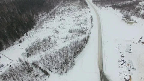 Flying above rural road through forest in bad winter cloudy day with snowfall. Stock Footage 92854022