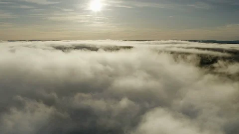 Flying above thick fluffy winter clouds and large winter Sun to clear blue sky Stock Footage 124612169