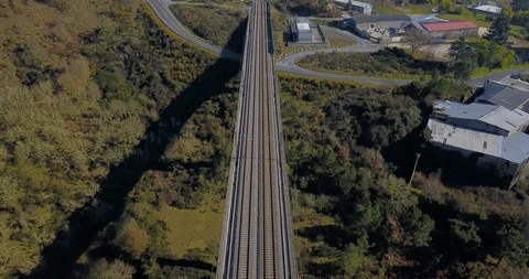 FLYING ABOVE THE TRAIN BRIDGE IN A GREEN VALLEY AND APPROACHING TO THE TUNNEL Stock Footage 103288529