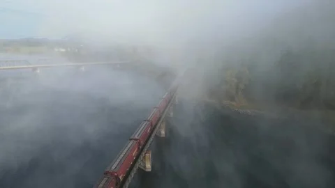 Flying above train going over river on bridge in fog - 4K aerial Stock Footage 163606623
