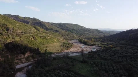 Flying Above Winding River Between Hills With Sun Creating Shadows Video stock 255704550