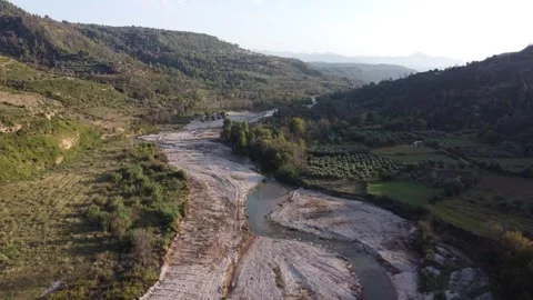 Flying Above Winding River Between Hills With Sun Creating Shadows Video stock 255705067