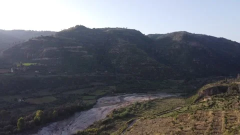 Flying Above Winding River Between Hills With Sun Creating Shadows Video stock 255705470